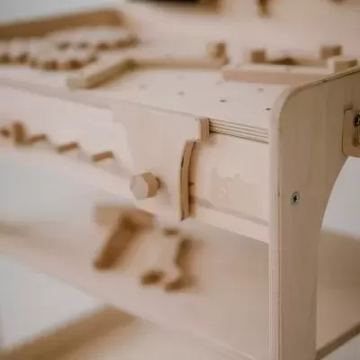 Bancada de trabalho infantil de madeira clara com ferramentas em madeira