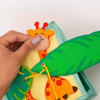 Livro de tecido para bebés com folhas verdes e girafa amarela com pintas laranja