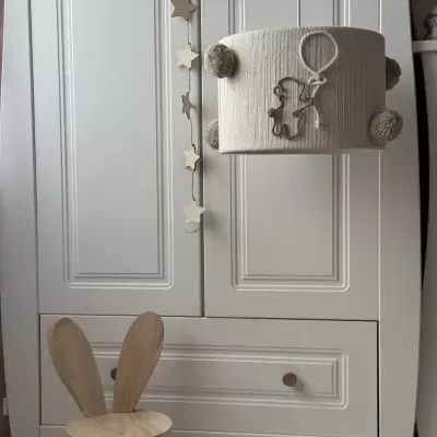 Armário branco com decoração de estrelas e candeeiro com ursinho, cadeira de madeira para crianças