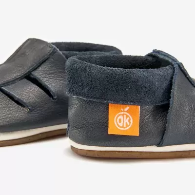 Sapatos infantis de pele azul escura com etiqueta laranja e sola castanha