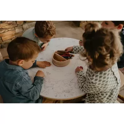 Crianças a colorir desenhos numa mesa redonda branca com lápis de cor