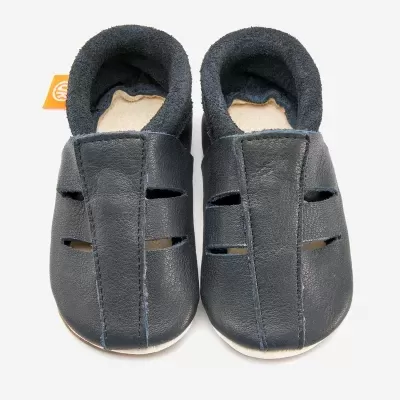 Sapatinhos para bebé em pele azul escuro com interior forrado cinzento e etiqueta laranja.