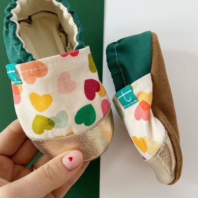 Sapatinhos infantis com padrão de corações coloridos e biqueira dourada