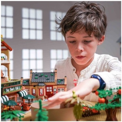 Conjunto de blocos de construção LEGO de vila com edifício, árvores e criança a brincar