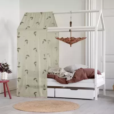 Cama branca com estrutura em forma de casa e cortina bege com padrão de guarda-chuvas