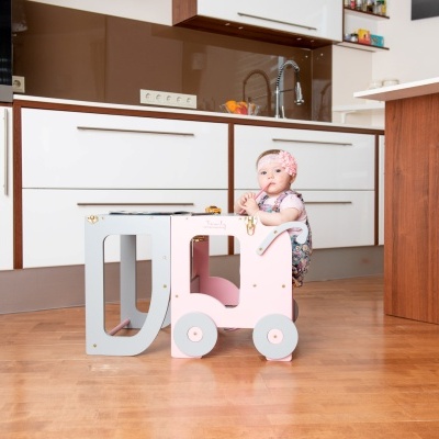 Carrinho de brincar para crianças com letras D e L em madeira e rodas cor-de-rosa e azul numa cozinha moderna