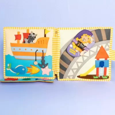 Livro macio infantil com ilustrações coloridas e brinquedos em tecido.