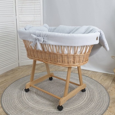 Berço de bebé em vime com forro branco em ambiente interior