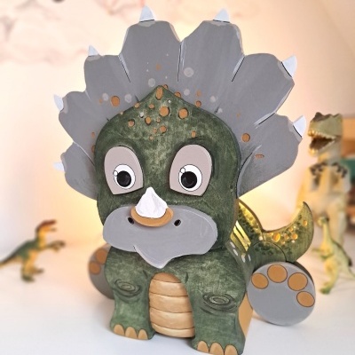Figura de dinossauro triceratops verde em material liso com detalhes cinza e laranja