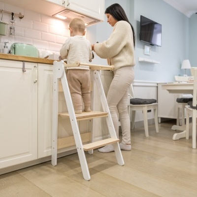 Menino em escada branca na cozinha, acompanhado por mulher, com uma torradeira verde pastel no balcão