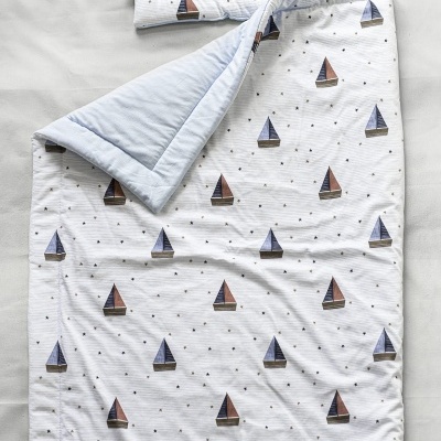 Conjunto de cama infantil com padrão de barcos azuis e castanhos em tecido branco
