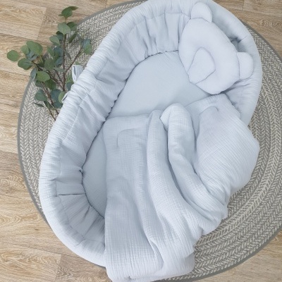 Ninho para bebé branco com almofada de urso colocado sobre tapete redondo cinzento