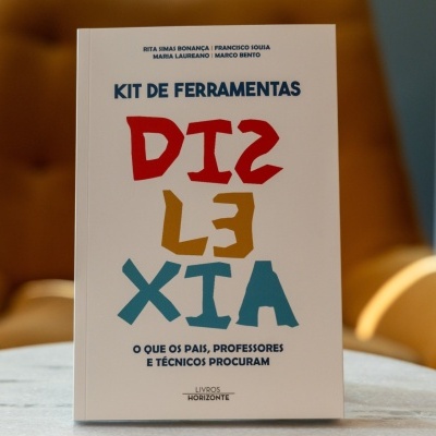 Livro KIT DE FERRAMENTAS DISTÁXIA com capa branca em mesa cinzenta e poltrona castanha ao fundo