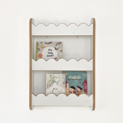 Estante de parede para livros infantis em madeira clara com prateleiras brancas e três livros expostos