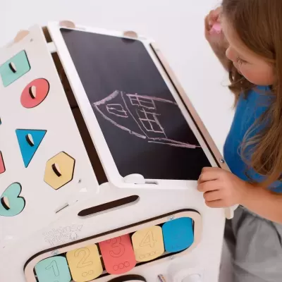 Centro de atividades infantil em madeira com painéis coloridos e quadro negro com desenho a giz.