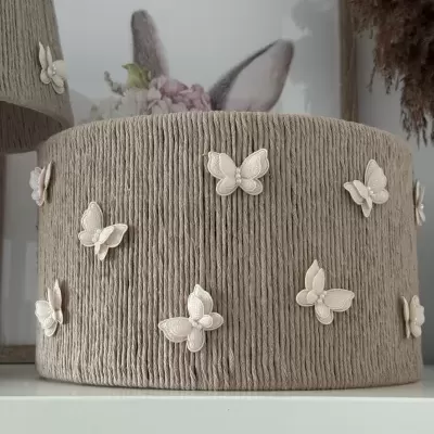 Apliques decorativos de borboletas creme em tecido bege com textura canalé.