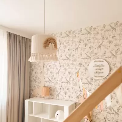 Candeeiro de tecto com bordado de leão numa divisão com papel de parede de animais e plantas e móvel branco