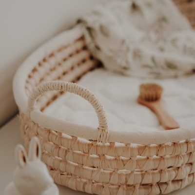 Cesto de verga com almofada branca e escova de madeira, garrafa branca com tampa de coelho.