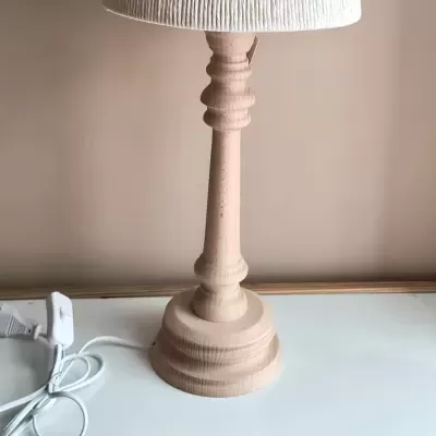 Candeeiro de mesa de madeira bege com abajur branco sobre superfície branca