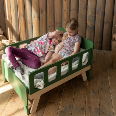 Cama verde para crianças em madeira com colchão branco e duas crianças deitadas