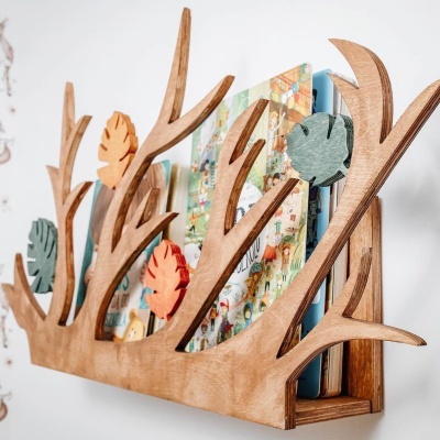 Prateleira de madeira com design de galhos e folhas coloridas a segurar livros