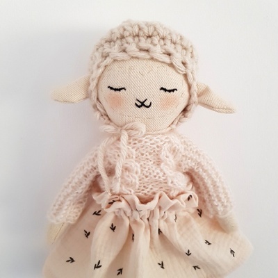 Boneca de tecido com roupas em tons rosa claro e bege, cabelo enrolado, e saia com padrão