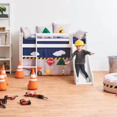 Cama branca infantil com escorrega e decoração temática de construção com cones e ferramentas de brinquedo