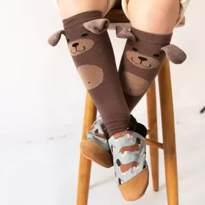Meias castanhas com desenho de urso e orelhas 3D em criança sentada