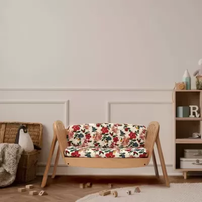 Sofá infantil de madeira com almofadas florais em ambiente com brinquedos e decoração