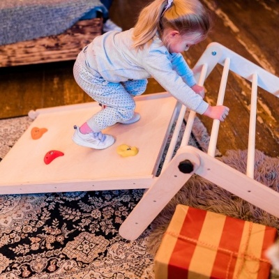 Menina a brincar com brinquedo de madeira com rampa e barras em ambiente doméstico
