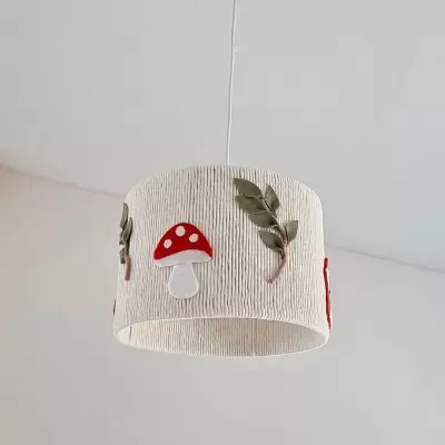 Lustre suspenso com abajur cilíndrico em tecido bege decorado com cogumelos vermelhos e folhas verdes