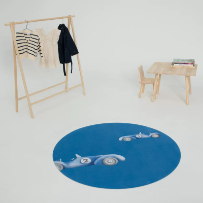 Tapete redondo azul com carros de corrida, cabide de madeira com roupas e mesa pequena