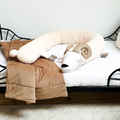 Cama com almofada em forma de ovelha e colcha marrom