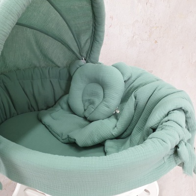 Berço portátil verde água com almofada de cabeça de urso acolchoada e suporte branco.