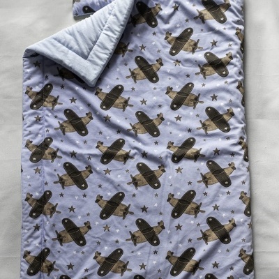 Conjunto de edredão e almofada azul com padrão de aviões e estrelas castanhos