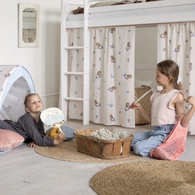Cama alta branca com cortinas de sereias e duas crianças brincando numa tenda com o mesmo padrão.