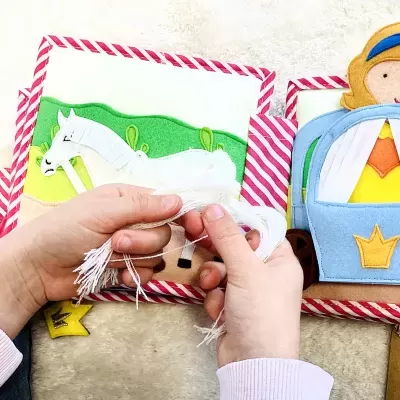 Livro infantil de tecido com cavalo branco e cavaleiro colorido em feltro