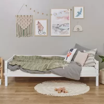 Cama infantil branca com roupa de cama e decoração de parede em macramé e quadros
