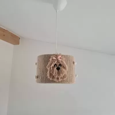 Abajur bege pendurado no teto com figura de cão de pêlo comprido e laço cor-de-rosa