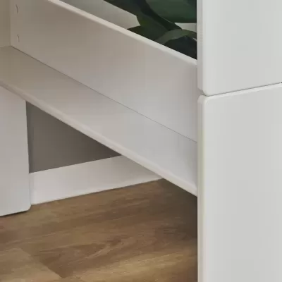 Móvel branco de design minimalista com planta verde numa sala com chão de madeira