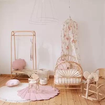 Quarto infantil com móveis em rattan e decoração suave em tons rosa e branco