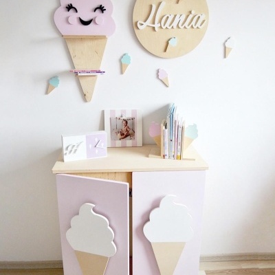 Móvel infantil com decoração de gelados em madeira e parede decorada com relógio e gelados em cores pastel.