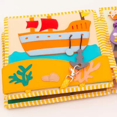 Livro de tecido com ilustração de barco e âncora de feltro colorido