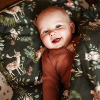 Bebé enrolado em cobertor com padrão de animais da floresta, vestido com camisola castanha