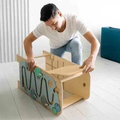 Brinquedo infantil educativo em madeira sendo montado por um homem.