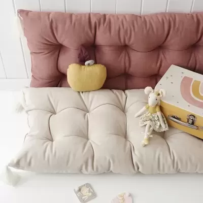 Almofadas terracota e bege, brinquedo de rato, mala decorativa e cartões sobre superfície branca