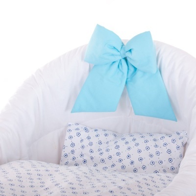 Berço branco com almofada e edredão padrão azul e branco e laço azul claro na cabeceira