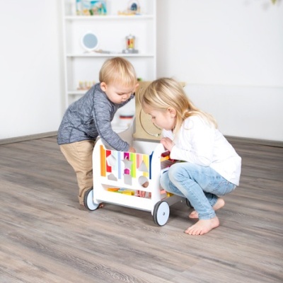 Crianças brincando com carrinho de brinquedo de madeira colorida em piso de madeira