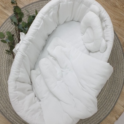 Berço para bebé branco acolchoado sobre tapete cinza redondo