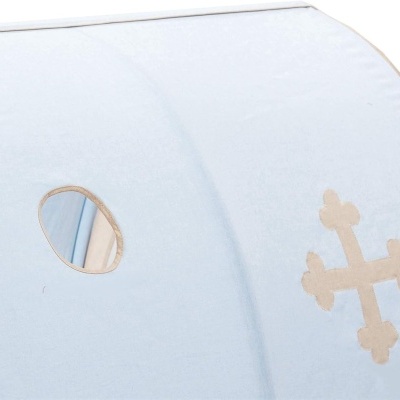 Têxtil azul claro com bordas bege, orifício oval e bordado em forma de cruz bege.